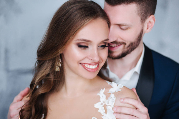 Beautiful wedding couple at home. They kiss and hug each other - Фото, изображение