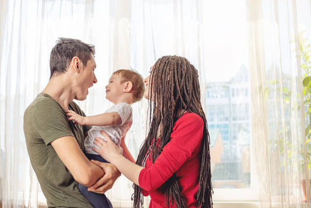 Szczęśliwy rodzice ojciec i matka bawiąc się z dzieckiem syna na rano. Wesoła i nowoczesna młoda rodzina - Zdjęcie, obraz