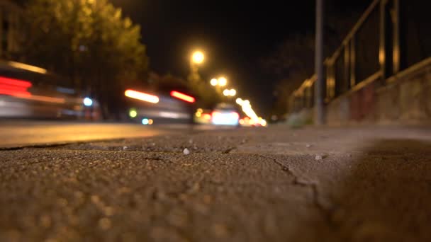 夜間に高速道路を走行する歩道やぼやけた車。ローアングルショットセレクティブフォーカス. - 映像、動画