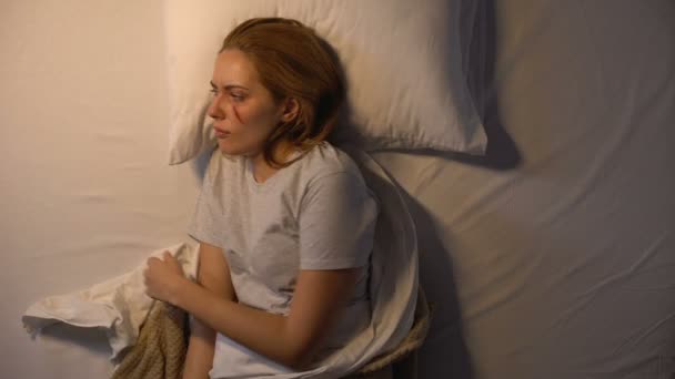 Sad injured woman switching off light and falling asleep, psychological trauma - Кадры, видео