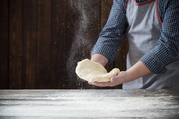  hands cooking dough on dark wooden background - Foto, afbeelding