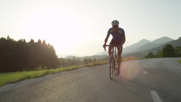 Atletik genç erkek yoğun dağ yarışı sırasında onun serin yol bisikleti pedallar üzerinde adım. Güneşli dağlarda Pro yol bisikletçi eğitimi. Yaz doğasında pitoresk bisiklet yolculuğu. Yavaş hareket görüntüleri - Video, Çekim