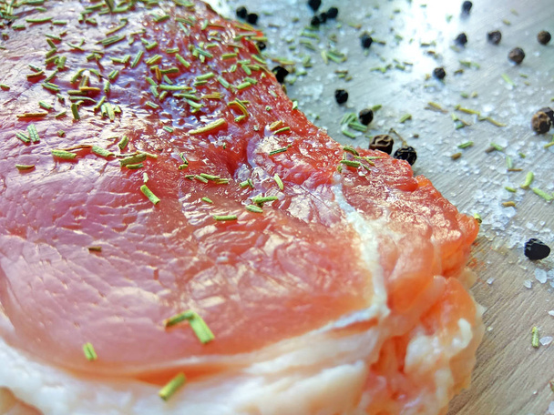 Carne orgánica de chuleta de cerdo cruda con sal, pimienta y romero lista para cocinar sobre fondo de tabla de cortar de madera. Enfoque selectivo cerca de la fotografía
 - Foto, Imagen