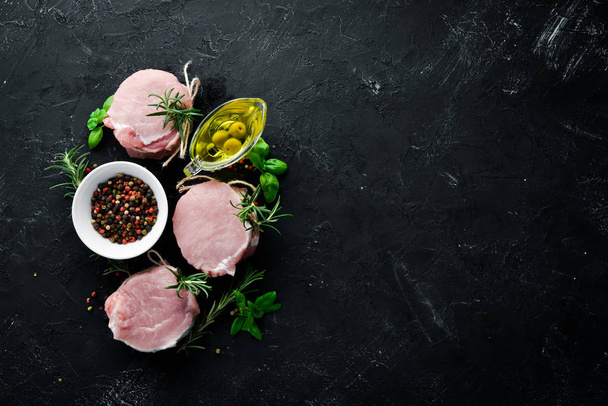 Raw meat, medallions with rosemary and spices. On a black stone background. Top view. Free copy space. - Photo, Image