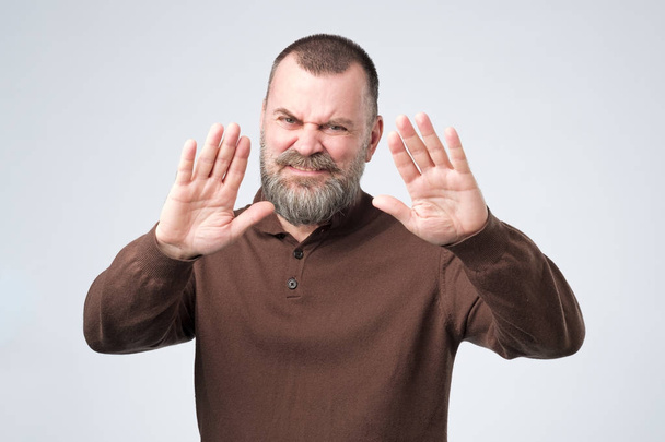Hombre maduro con barba muestra gesto de rechazo, no quiere hablar con usted
 - Foto, Imagen