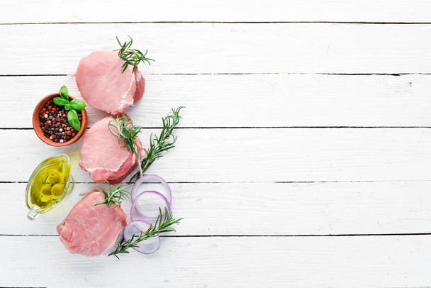 Raw meat, medallions with rosemary and spices. On a white wooden background. Top view. Free copy space. - Foto, Imagem