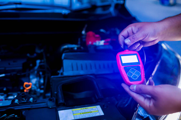 Mechaniker hält Batterietester nach Batteriewechsel in der Hand - Foto, Bild