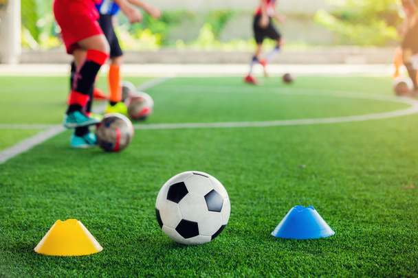 fútbol entre conos marcador en césped artificial verde
 - Foto, Imagen