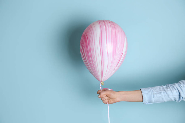 Female hand with air balloon on color background - Фото, изображение