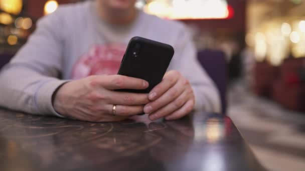 Iphone を使ってカフェのテーブルに座っている若いビジネスマン。メッセージを入力すると、成功した人、毎日のルーチン - 映像、動画