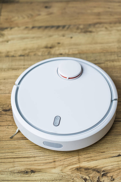 Robot vacuum cleaner on wooden floor. Side view. Smart home concept. Automatic cleaning. - 写真・画像