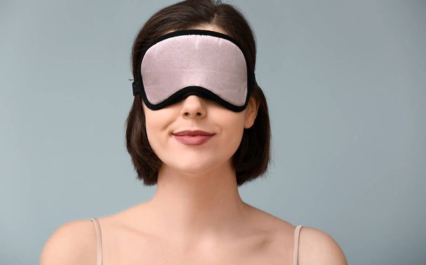Young woman with sleep mask on color background - Фото, зображення