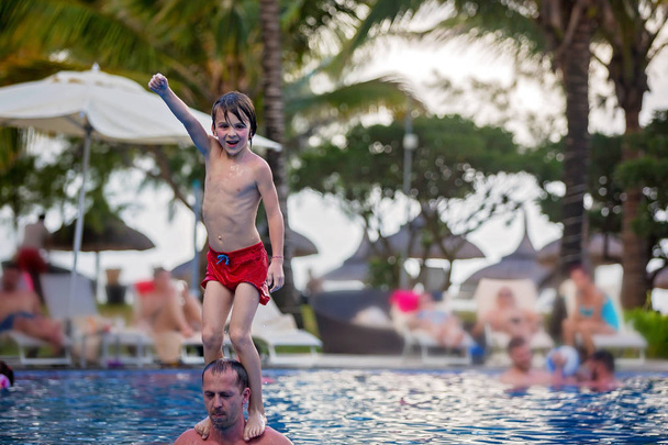 Симпатичний хлопчик, стрибає в басейні з плечей тата
 - Фото, зображення
