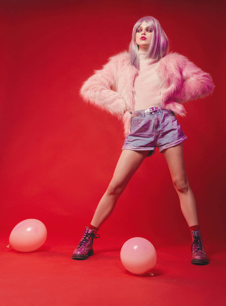 Cheeky girl on pink background in body, fur coat, boots. Pretty  - Photo, Image