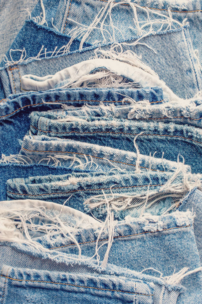 A collection of old jeans on a blue background. Problems of consumer society. - Фото, зображення