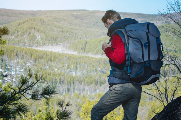 大きなバックパックを持つ男性観光客は、岩の崖の上に立って、広大な緑の谷を見ています。旅行の自由 - 写真・画像