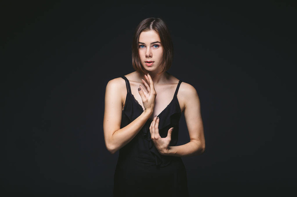 Portrait d'une belle jeune femme caucasienne de 20 ans modèle aux yeux bleus maquillage naturel de cheveux sur épaule dansant les mains posant sur fond noir isolé en lingerie noire
 - Photo, image