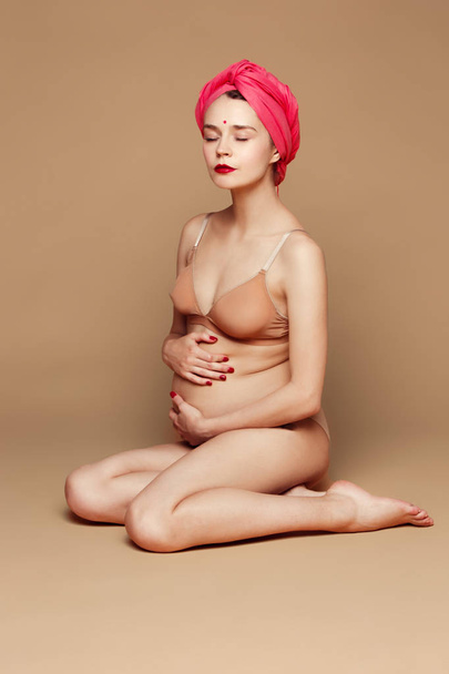 Young beautiful pregnant woman posing on brown background - Φωτογραφία, εικόνα