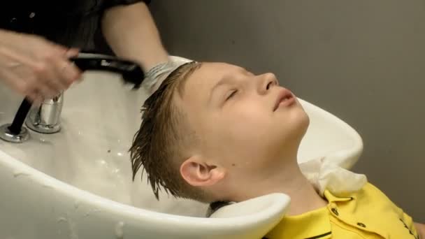 coiffeur lave le garçon de tête dans le salon - Séquence, vidéo