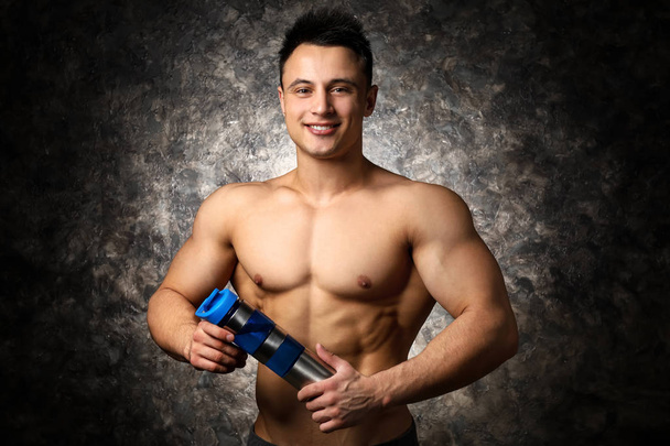 Sportovní muž s bílkovinným protřepávat na tmavém pozadí - Fotografie, Obrázek