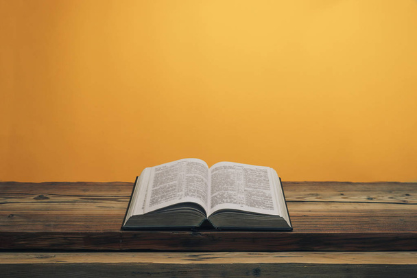 Otevřete Bibli svatou na starém dubovém dřevěném stole. Pomerančové pozadí. - Fotografie, Obrázek