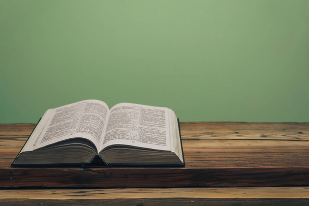 Ouvrez la Bible Sainte sur une vieille table en bois de chêne. Arrière-plan mur vert. - Photo, image