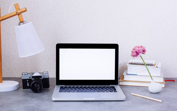 Vista frontal del escritorio con ordenador portátil en blanco y elementos decorativos
   - Foto, Imagen