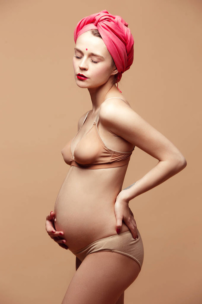 Young beautiful pregnant woman posing on brown background - Photo, Image