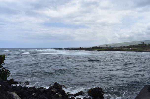 Olas que se estrellan en Rocky Shore en Hawaii espuma blanca mientras las olas se lavan sobre las rocas bajo un cielo azul
 - Foto, imagen