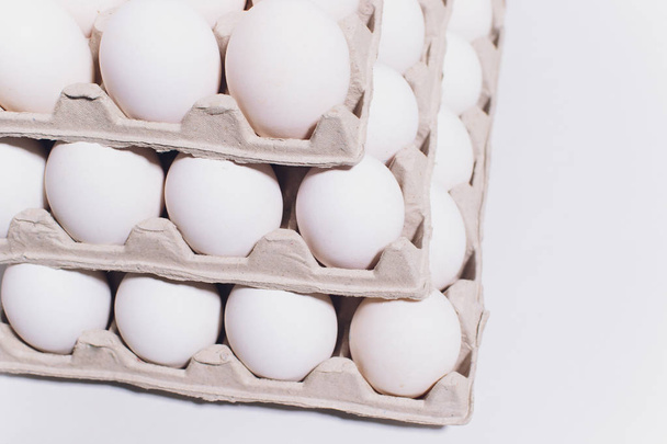 Білі яйця курки в нешкідливій картонній упаковці на білому тлі. 3 пакети
. - Фото, зображення