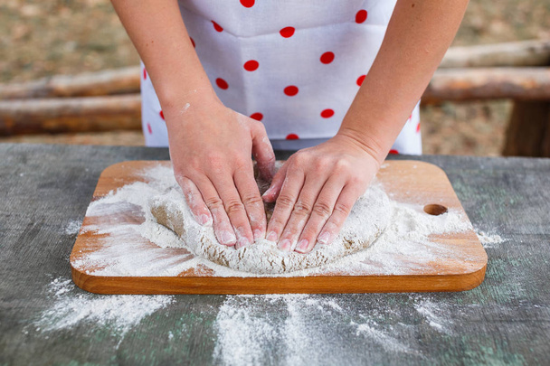 Women's hands knead the dough of dark rye flour - Foto, imagen