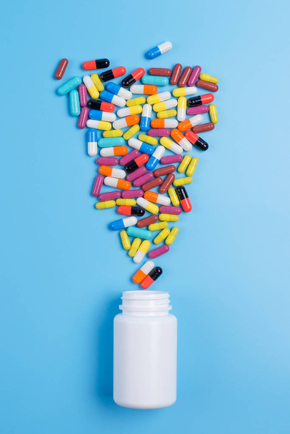 Medicina píldoras o cápsulas verdes, amarillas y rosadas y bott blanco
 - Foto, Imagen