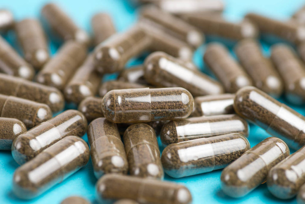 Pilules brunes, comprimés sur fond bleu. Photographie en gros plan de
 - Photo, image