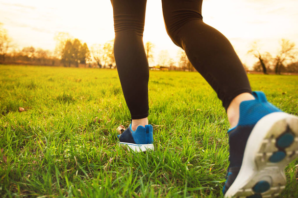 Runner athlete feet running on grass.Male fitness sunlight jogging workout. Sport athlete active lifestyle concept.Athletic pair of legs running on grass during sunset city park. - Foto, imagen