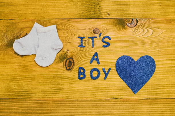 Text it's a boy with baby boy socks and heart shape on wooden table.Toned photo. - Foto, imagen