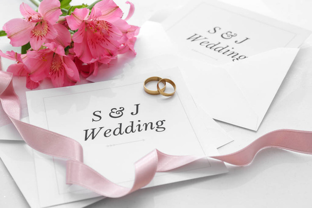 Esküvői meghívók, gyűrűk és virágok az asztalnál - Fotó, kép