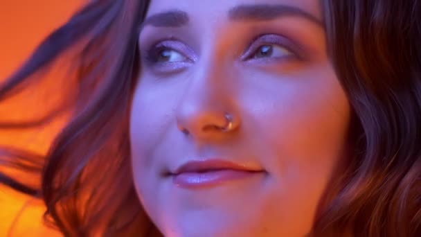 Close-up schieten van jonge offerte Kaukasische vrouw met mooie make-up te kijken naar camera met neon rode achtergrond - Video