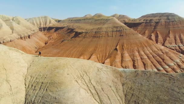 Turist adam tepenin boyunca yokuş yukarı yürürken yükselir. Çöl arazisi. Havadan video çekimi. Kretase Dağları Aktau. Altyn-Emel Milli Parkı. Kazakistan - Video, Çekim