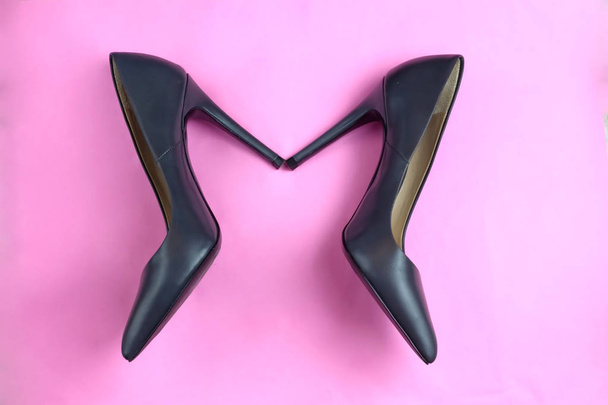 Μοντέρνα αίγλη φανταχτερό μαύρο δέρμα κλασικό ζευγάρι κομψό ψηλό τακούνια παπούτσια σε ροζ φόντο - Φωτογραφία, εικόνα