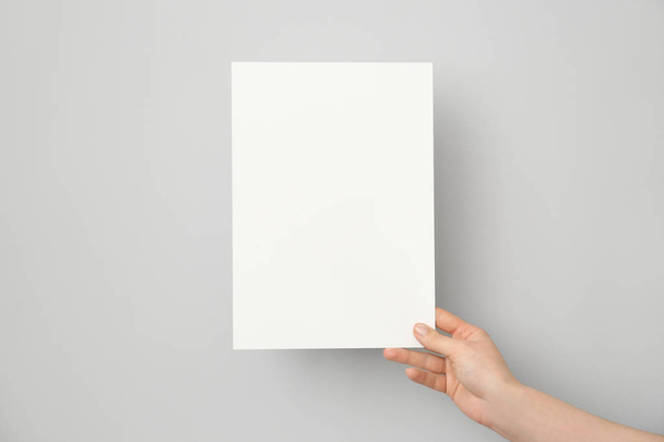 Mão feminina com cartão de convite em branco no fundo claro
 - Foto, Imagem