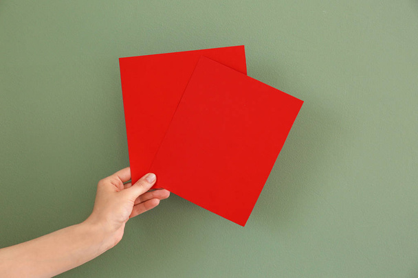 weibliche Hand mit leeren Einladungskarten auf farbigem Hintergrund - Foto, Bild