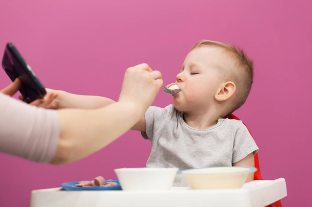 O rapazinho não quer comer puré de batata. Criança toma café da manhã em casa, enquanto assiste desenhos animados no tablet
 - Foto, Imagem