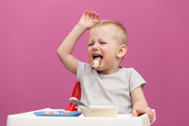 Pikkupoika ei halua syödä perunamuusia. Lapsi syö aamiaista kotona, katsoessaan sarjakuva tabletilla
 - Valokuva, kuva