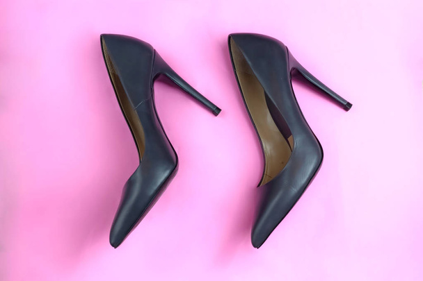 Μοντέρνα αίγλη φανταχτερό μαύρο δέρμα κλασικό ζευγάρι κομψό ψηλό τακούνια παπούτσια σε ροζ φόντο - Φωτογραφία, εικόνα
