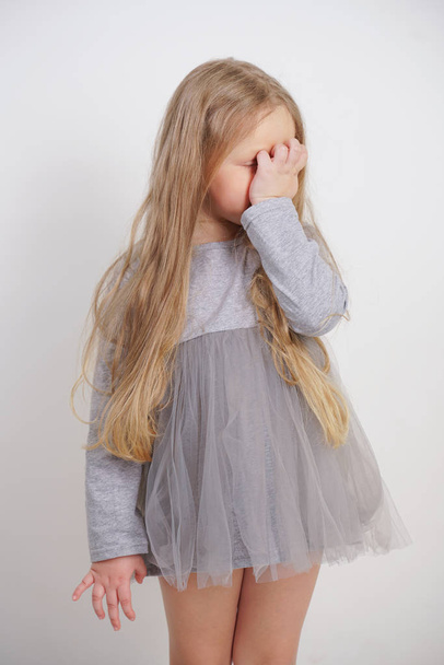 little girl child standing with a hand in the face with facepalm symbol on white background in Studio - 写真・画像