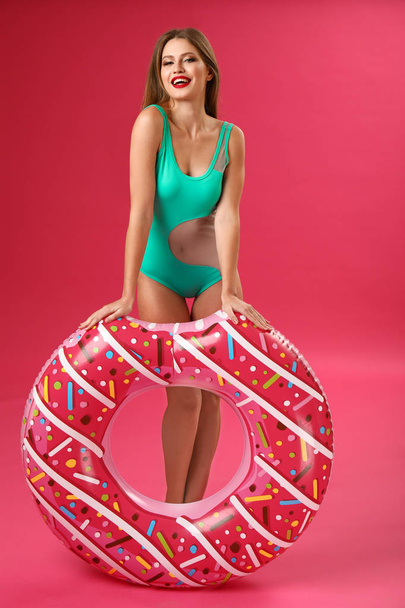 mooie jonge vrouw met opblaasbare ring op kleur achtergrond - Foto, afbeelding