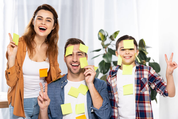cheerful parents and cute kid in sticky notes showing peace signs  - Photo, Image