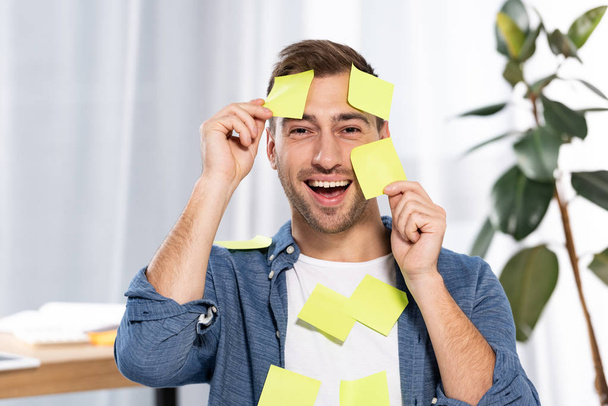 happy man in yellow and orange sticky notes looking at camera - Foto, Bild