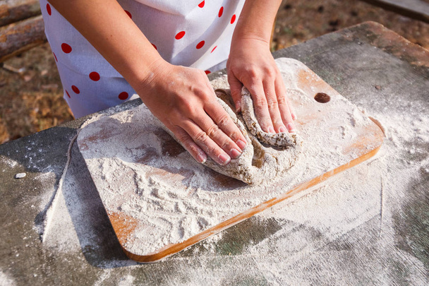 Women's hands knead the dough of dark rye flour - Fotoğraf, Görsel