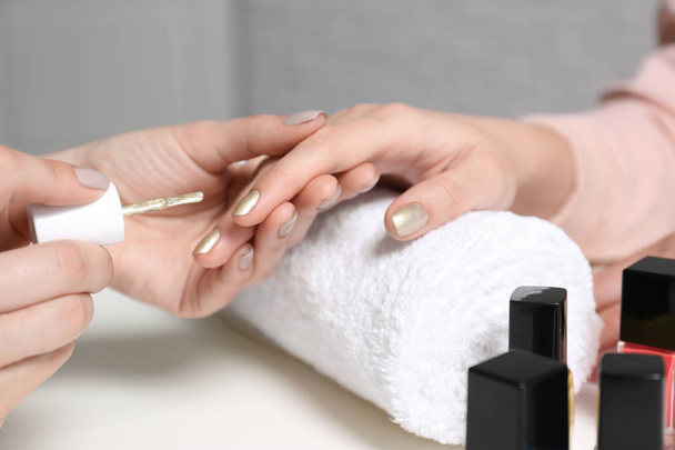 Manicurist painting client's nails with polish in salon, closeup - Fotó, kép
